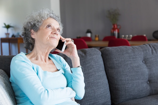 Retrato de mujer senior pensativa hablando por teléfono móvil