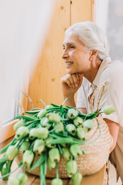 Retrato de mujer senior sonriente con cesta de tulipanes