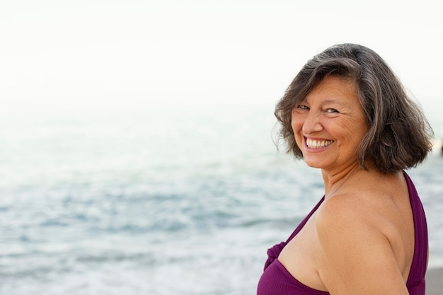 Foto gratuita retrato de mujer senior sonriente en la playa.