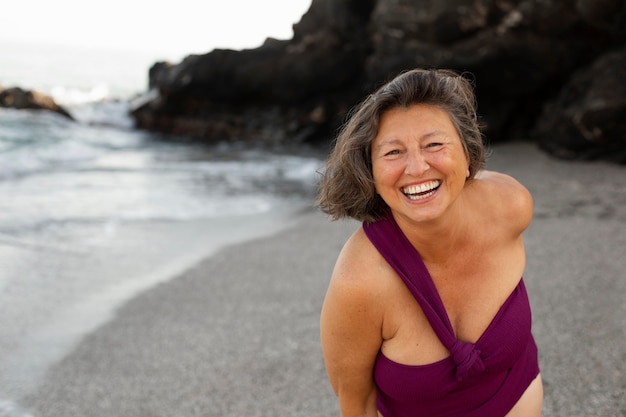 Foto gratuita retrato de mujer senior sonriente en la playa.