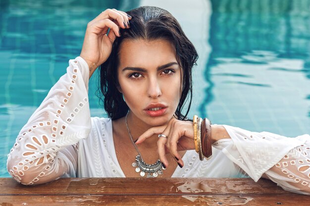 Retrato de mujer sensual increíble con cuerpo bronceado perfecto posando en la piscina