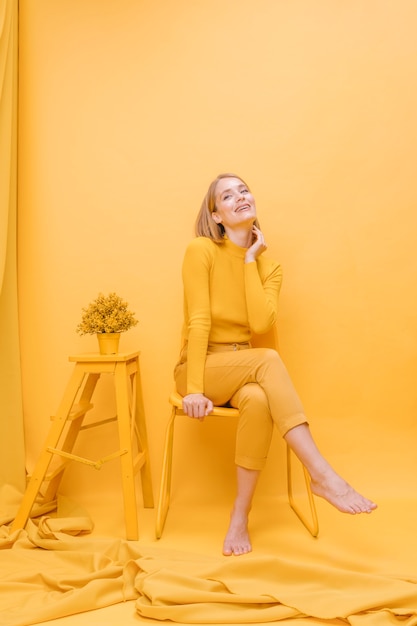 Retrato de mujer sentada en un escenario amarillo