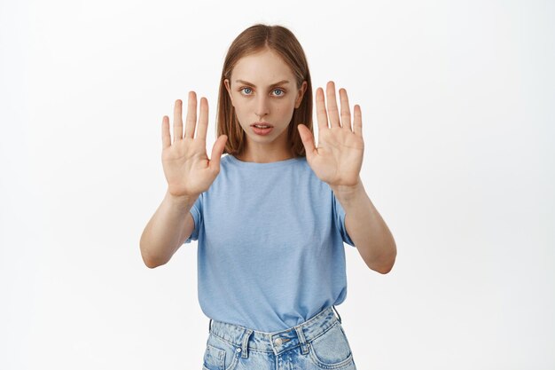 Retrato de una mujer seria y segura de sí misma, extender las manos, hacer un gesto de parada tabú, decir no, estar en desacuerdo y prohibir algo malo, rechazar, decir retroceder, alejarse, fondo blanco.