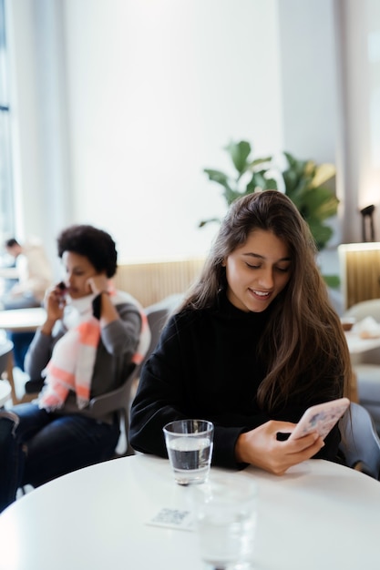 Retrato de mujer con smartphone mientras está sentado en la cafetería