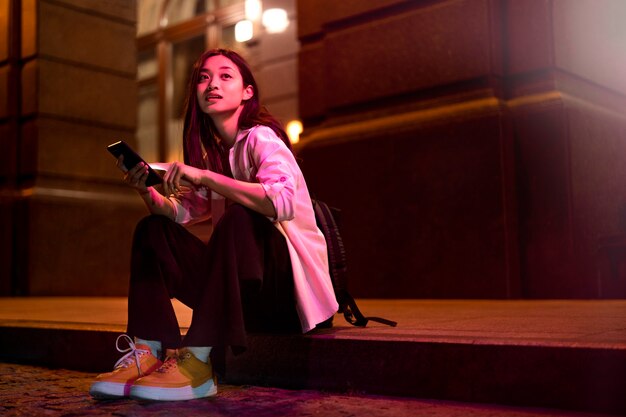 Retrato de mujer con smartphone por la noche en las luces de la ciudad