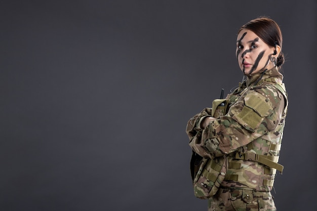 Retrato de mujer soldado en camuflaje en la pared oscura