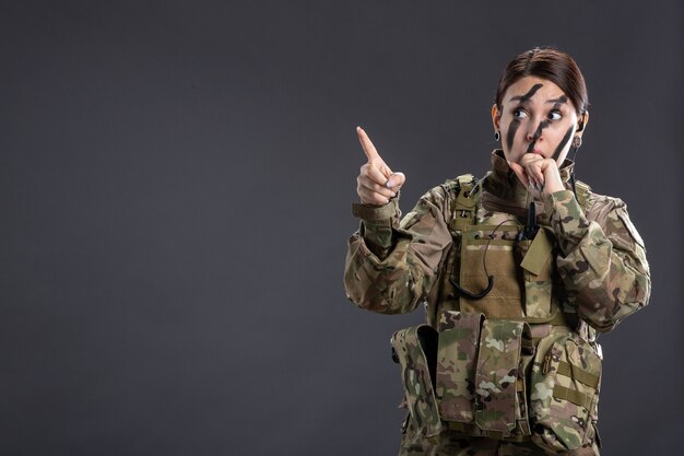 Retrato de mujer soldado en uniforme militar pared oscura