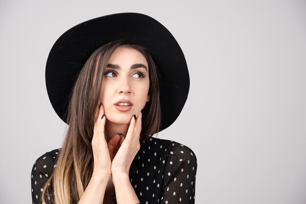 Retrato de mujer con sombrero negro mirando a su lado.