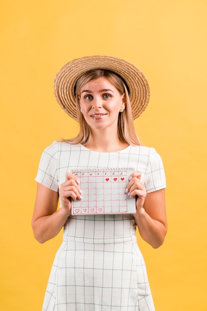 Retrato de una mujer con sombrero sosteniendo su calendario menstrual