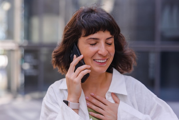 Retrato de mujer sonriendo con los ojos cerrados hablando por teléfono celular