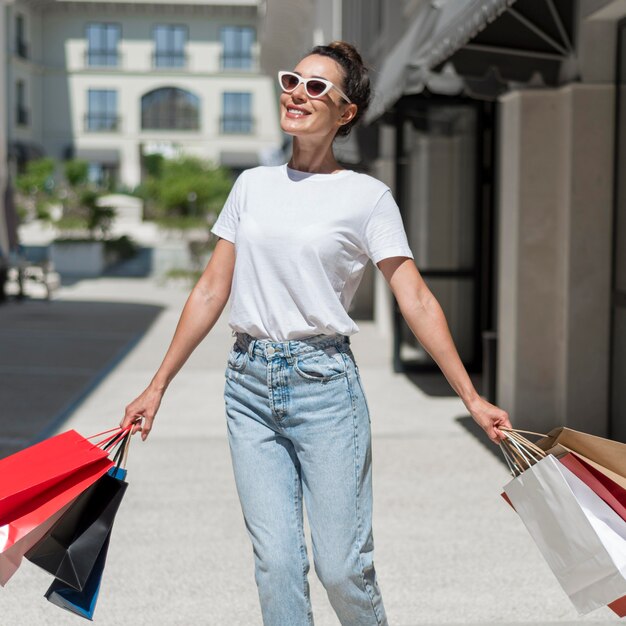 Retrato de mujer sonriente caminando con bolsas de la compra.
