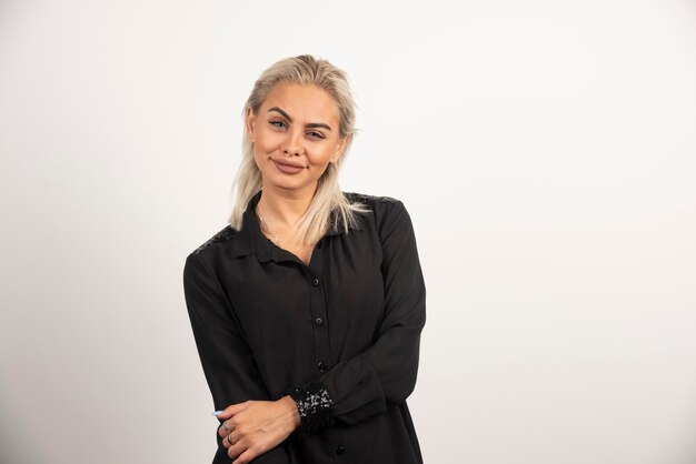 Retrato de mujer sonriente en camisa negra posando sobre fondo blanco. Foto de alta calidad