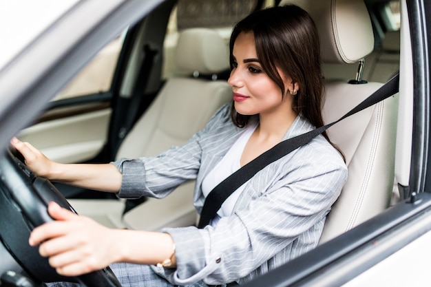 Retrato de mujer sonriente conductora abrocharse el cinturón de seguridad antes de conducir un coche.