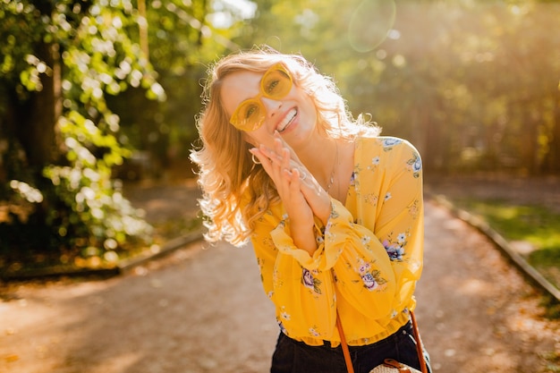 Retrato de mujer sonriente elegante rubia hermosa en blusa amarilla con gafas de sol