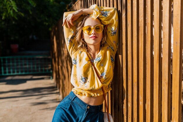 Retrato de mujer sonriente elegante rubia hermosa en blusa amarilla con gafas de sol