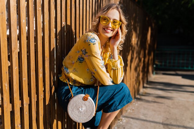 Retrato de mujer sonriente elegante rubia hermosa en blusa amarilla con gafas de sol