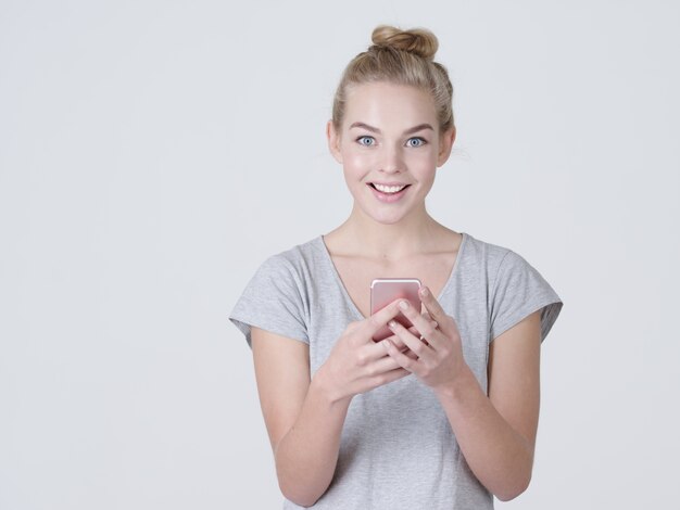 Retrato de una mujer sonriente está escribiendo un mensaje de texto en el teléfono móvil - en el estudio