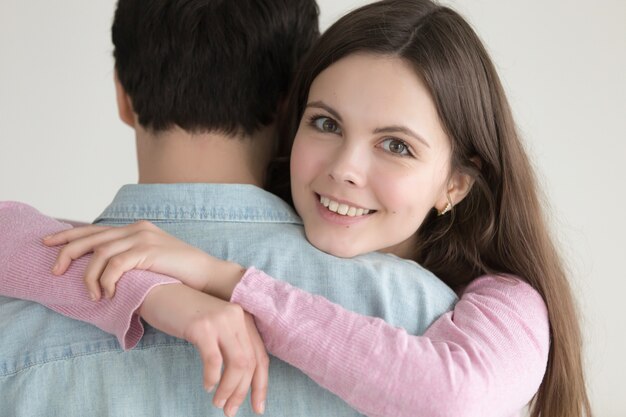 Retrato de la mujer sonriente feliz joven que abraza al hombre con amor