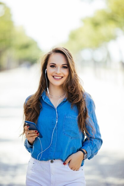 Retrato de mujer sonriente feliz de pie en la plaza en verano soleado o día de primavera afuera, linda mujer sonriente mirándote, chica joven atractiva disfrutando del verano, imagen filtrada, destello de sol