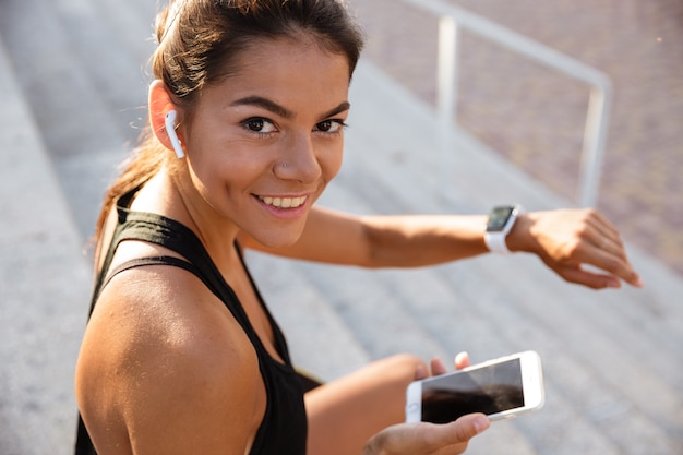 Retrato de una mujer sonriente de fitness en auriculares