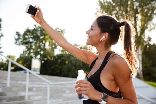 Foto gratuita retrato de una mujer sonriente de fitness en auriculares