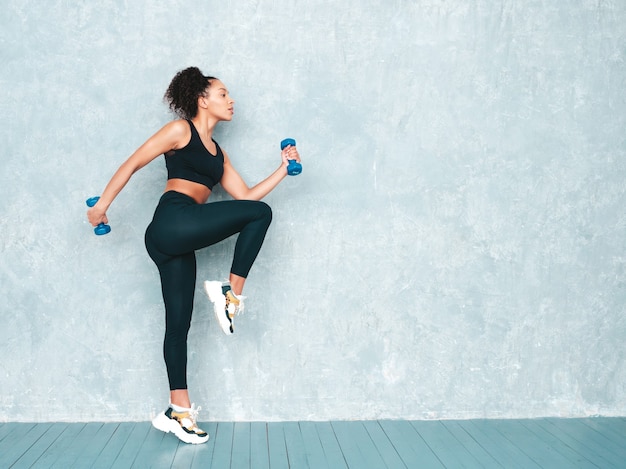 Retrato de mujer sonriente fitness en ropa deportiva con peinado de rizos afro