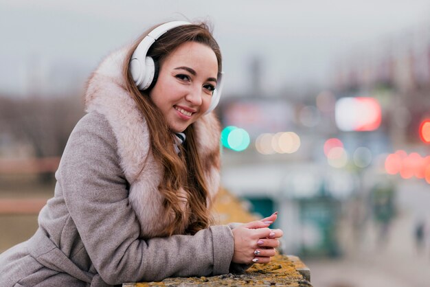 Retrato de mujer sonriente fotogénica con auriculares en techo