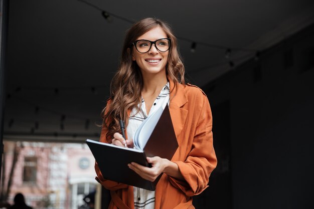 Retrato de una mujer sonriente haciendo notas