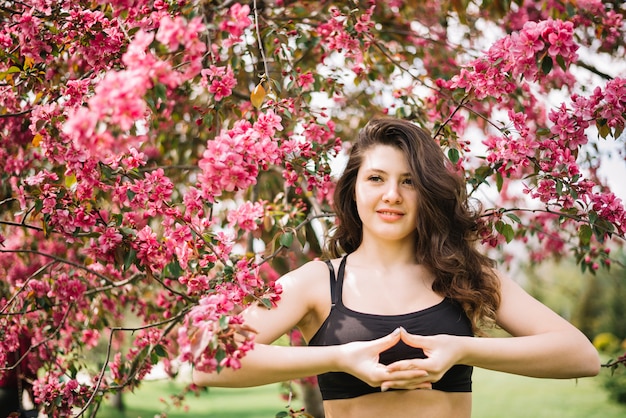 Retrato de mujer sonriente haciendo yoga mudra gesto en el parque