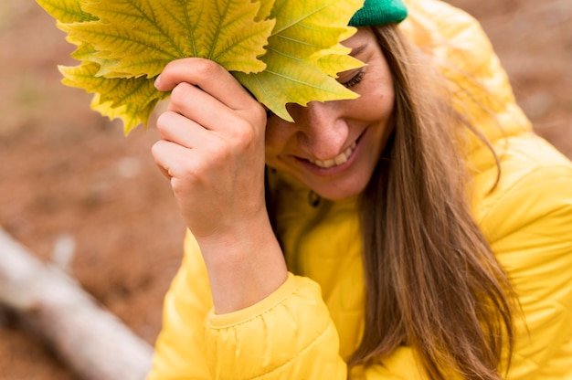 Retrato de mujer sonriente con hojas de otoño al aire libre