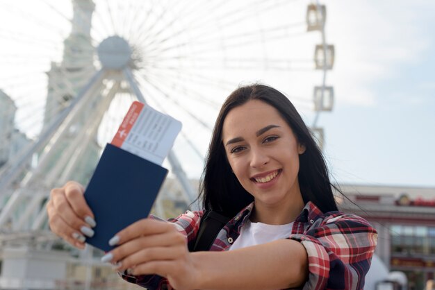 Retrato de mujer sonriente mostrando pasaje aéreo y pasaporte