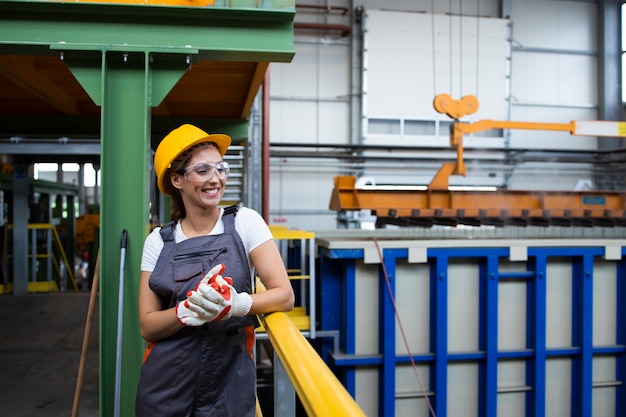 Retrato de mujer sonriente obrera de pie en la sala de producción industrial