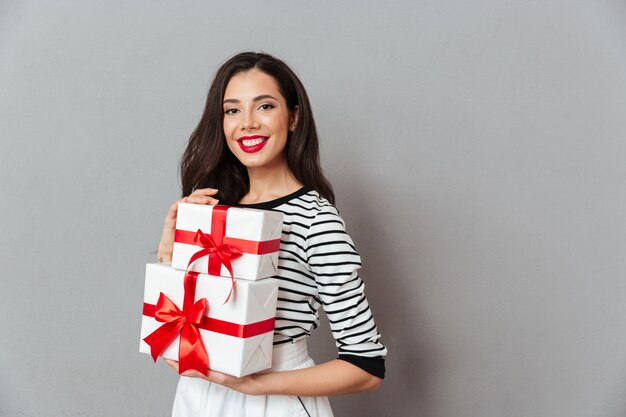 Retrato de una mujer sonriente con pila de cajas de regalo