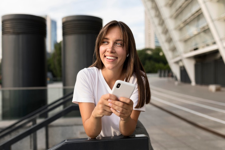 Foto gratuito retrato de mujer sonriente posando mientras sostiene su teléfono