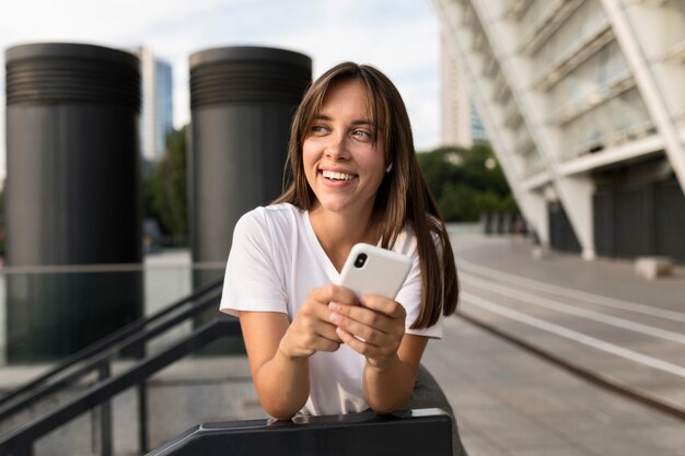 Retrato de mujer sonriente posando mientras sostiene su teléfono