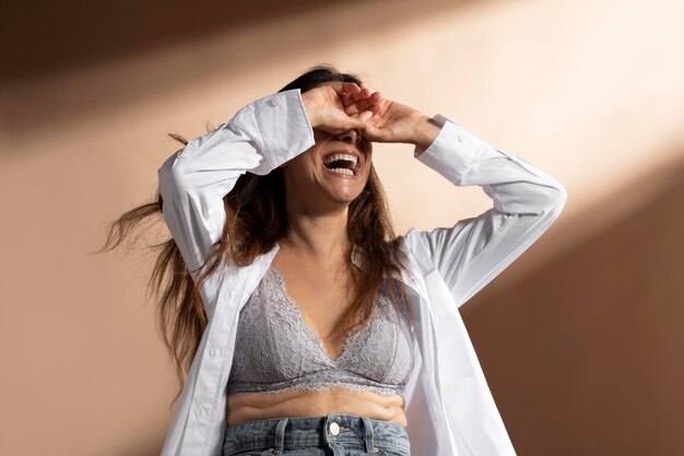 Retrato de mujer sonriente posando en sujetador y camisa blanca