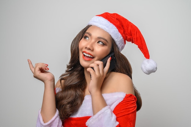 Retrato de mujer sonriente en rojo santa claus mostrando smartphone