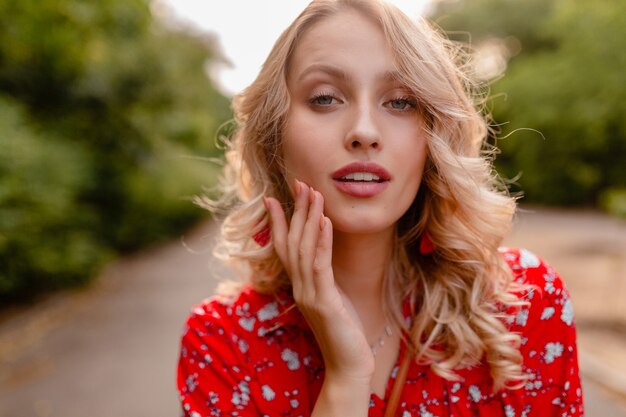 Retrato de mujer sonriente rubia elegante atractiva en traje de moda de verano blusa roja con aretes sonriendo