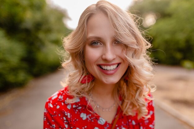 Retrato de mujer sonriente rubia elegante atractiva en traje de moda de verano blusa roja con aretes sonriendo