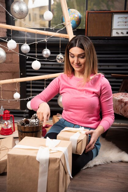 Retrato de mujer sonriente sentada con un regalo de Navidad.