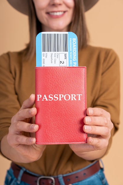 Retrato de mujer sonriente con sombrero sosteniendo pasaporte