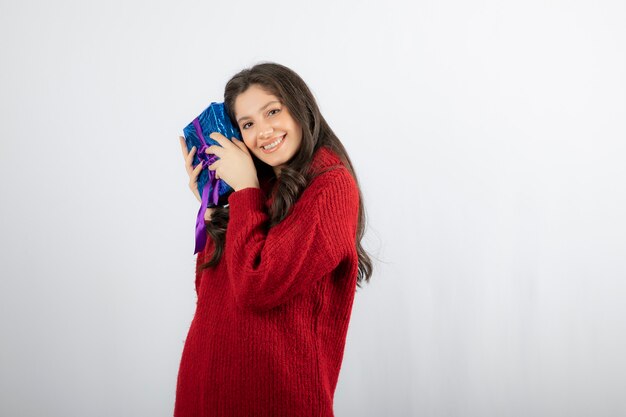 Retrato de una mujer sonriente sosteniendo una caja de regalo de Navidad con cinta morada.