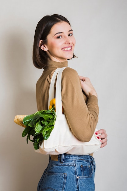 Foto gratuita retrato de mujer sonriente sosteniendo comestibles ecológicos