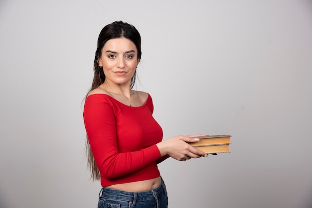 Foto gratuita retrato de una mujer sonriente sosteniendo dos libros