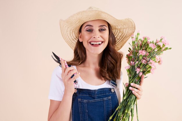 Retrato de mujer sonriente sosteniendo flores y tijeras de podar