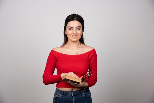 Retrato de una mujer sonriente sosteniendo un libro abierto.