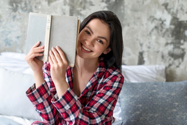 Retrato de mujer sonriente sosteniendo libro