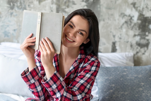 Retrato de mujer sonriente sosteniendo libro