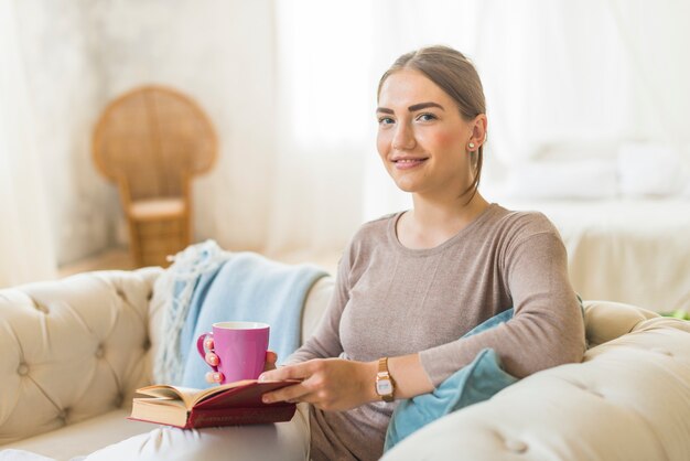 Retrato de una mujer sonriente con taza de café y libro