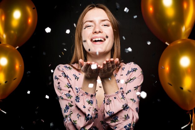 Retrato de mujer soplando confeti en la fiesta